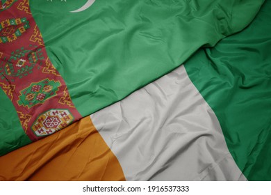 waving colorful flag of cote divoire and national flag of turkmenistan. macro