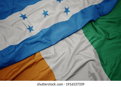 waving colorful flag of cote divoire and national flag of honduras. macro