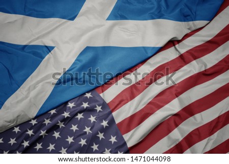 waving colorful flag of united states of america and national flag of scotland.