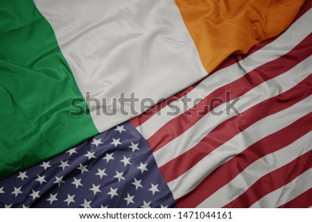 waving colorful flag of united states of america and national flag of ireland.