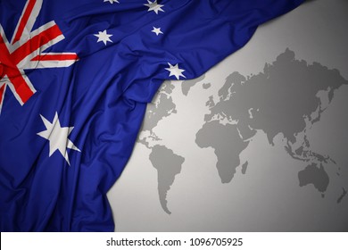 waving colorful national flag of australia on a gray world map background.