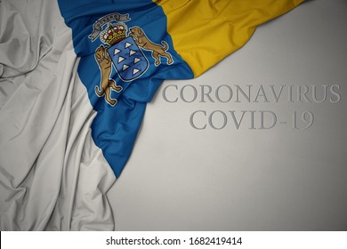 Waving Colorful National Flag Of Canary Islands On A Gray Background With Text Coronavirus Covid-19 . Concept.