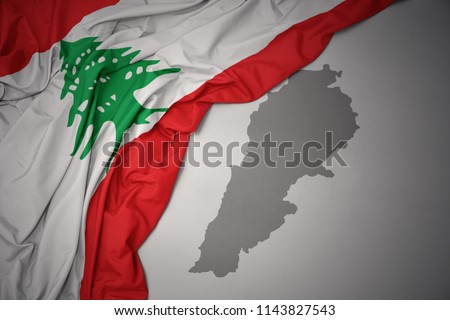 waving colorful national flag of lebanon on a gray map background.
