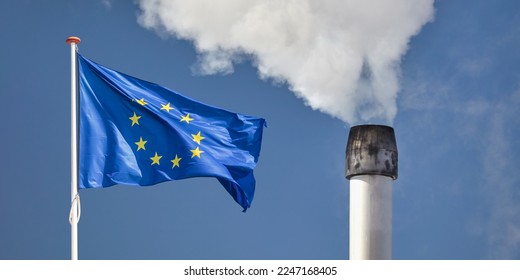 Waving European flag in front of a polluting factory chimney with smoke - Shutterstock ID 2247168405