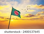 Waving flag of Bangladesh against the background of a sunset or sunrise. Bangladesh flag for Independence Day. The symbol of the state on wavy fabric.