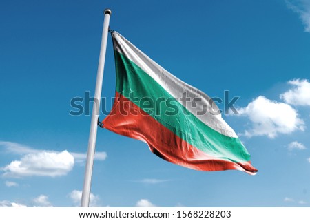 Waving Flag of Bulgaria in Blue Sky. Bulgaria Flag on pole for Independence day. The symbol of the state on wavy cotton fabric.