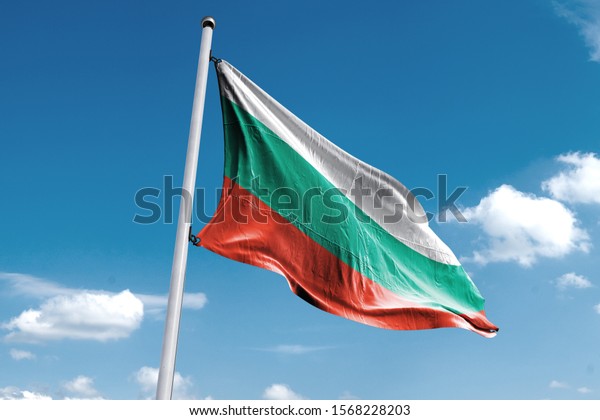 Waving Flag of Bulgaria in Blue Sky. Bulgaria\
Flag on pole for Independence day. The symbol of the state on wavy\
cotton fabric.