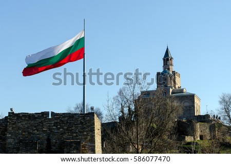 Waving flag of Bulgaria at Tsarevets fortress with patriarch church in background, Veliko Tarnovo, Bulgaria