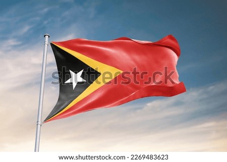 Waving flag of East Timor in beautiful sky. East Timor flag for independence day. The symbol of the state on wavy fabric.