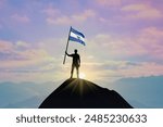 Waving flag of El Salvador at the top of a mountain summit against sunset or sunrise. El Salvador flag for Independence Day.