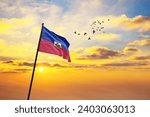 Waving flag of Haiti against the background of a sunset or sunrise. Haiti flag for Independence Day. The symbol of the state on wavy fabric.