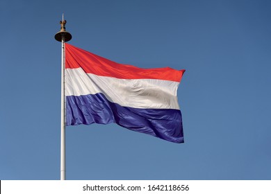 Waving Flag Of Holland On A Flag Poll Against Blue Sky