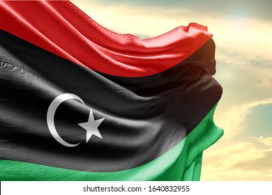 Waving Flag of Libya in Blue Sky. Libya Flag on pole for Independence day. The symbol of the state on wavy cotton fabric.