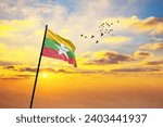Waving flag of Myanmar against the background of a sunset or sunrise. Myanmar flag for Independence Day. The symbol of the state on wavy fabric.