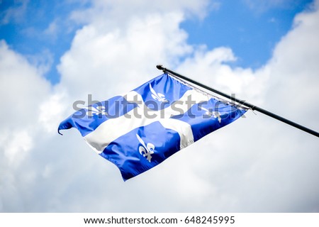 The waving flag of Quebec against the blue sky