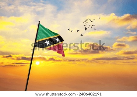 Waving flag of Saint Kitts and Nevis against sunset or sunrise. Flag for Independence Day. The symbol of the state on wavy fabric.