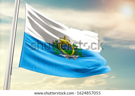 Waving Flag of San Marino in Blue Sky. San Marino Flag on pole for Independence day. The symbol of the state on wavy cotton fabric.