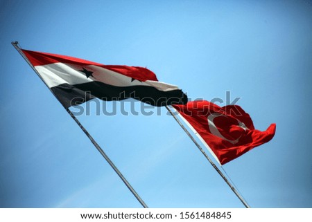 Waving flags of Syria and Turkey.