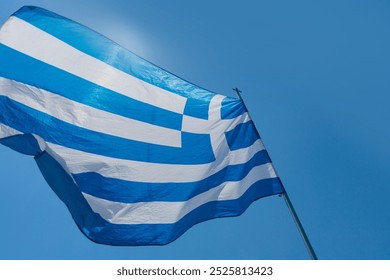 Waving Greek flag against a clear blue sky during a sunny day - Powered by Shutterstock