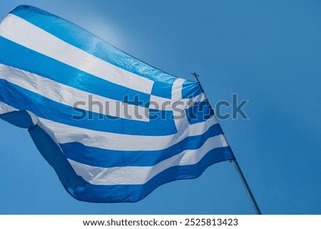 Waving Greek flag against a clear blue sky during a sunny day