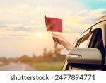 Waving the Morocco flag against the sunrise or sunset from a car driving along a country road. Holding the Morocco flag, traveling by car, on a weekend trip.