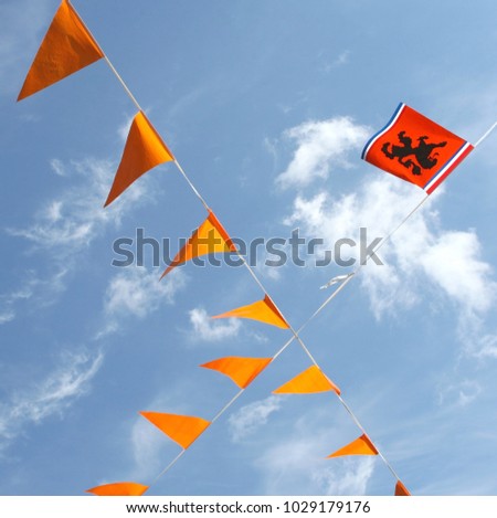 Waving orange flags with Dutch lion in a blue sky, Netherlands. Celebrations for public holidays (Bevrijdingsdag) and Fifa world cup football sport events
