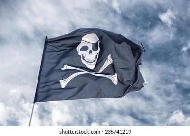 waving pirate flag jolly roger on sky background - Shutterstock ID 235741219