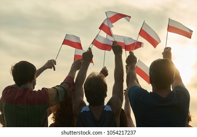 Waving Poland Flags. Back View Silhouette Of Polish Family.