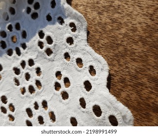 Wavy Edge Of A White Fabric With A Floral Print Of Small Round Embroidered Slits, On A Dark Wooden Background (macro, Top View, Texture).