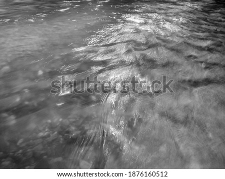 Wavy ripple surface of water on shallow rapid stream, landscape with abstract texture running water in creek, motion blur
