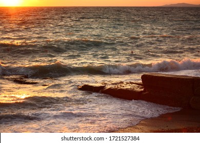 Wavy Sea Water And Concrete Block On Sand Beach. Relax Vacation Scenic Touristic Beach Coast Place. Marine Waves, Sunset And Mountain On Horizon Background. Evening Idyllic Landscape Horizontal Photo