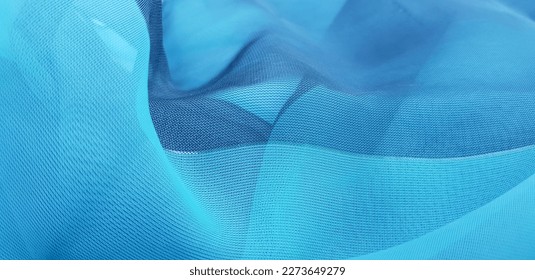 Wavy turquoise blue translucent fabric (chiffon) with a golden thread, in folds (macro, texture).
				