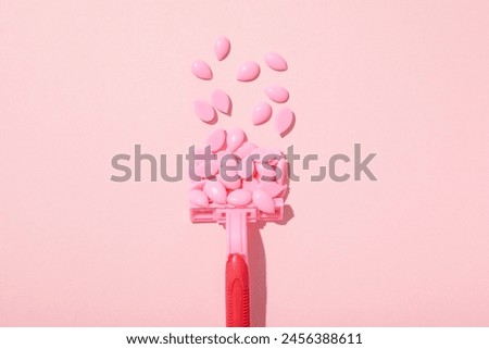 Wax granules for depilation with a razor on a pink background