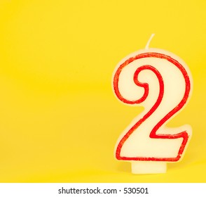 A wax red and white candle, number "two" on a yellow background