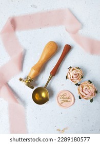 Wax stamp, spoon, thank you pattern wax coin on a white background, used to make wax coins for vintage antique wedding decoration or invitation. Flat lay image of wax stamp set with pink ribbon flower - Shutterstock ID 2289180577