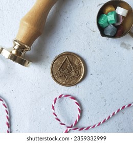 Wax stamp, triangle wreath pattern coin, spoon, colorful wax beads on a white background, used for vintage antique wedding decoration or invitation. Flat lay aesthetic image of wax stamp set. - Shutterstock ID 2359332999