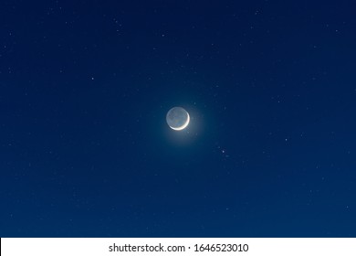 Waxing crescent moon, earthshine and starry night sky