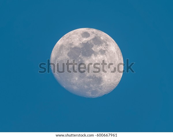 Waxing Gibbous phase of the Moon in the blue
morning sky background. Detailed craters. Closeup. The moon is in
the center.