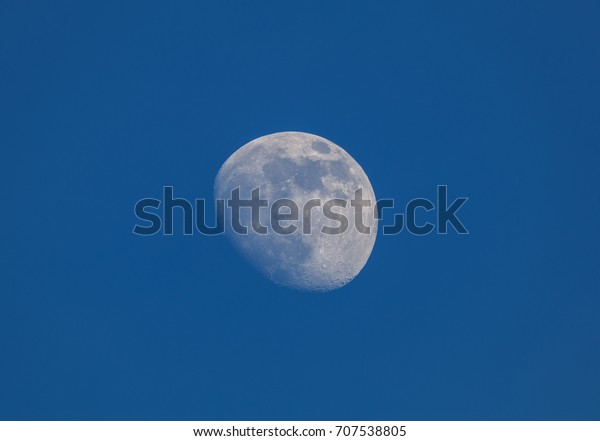 Waxing Gibbous Phase of the Moon in the\
blue morning sky background. Detailed\
craters