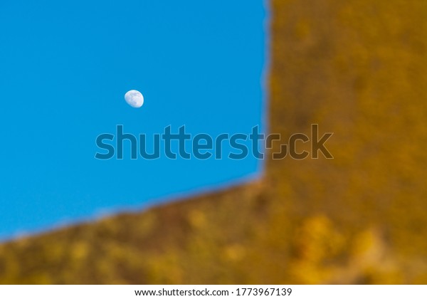 Waxing moon in the blue sky.\
Foreground is illuminated by the setting sun with warm colors.\
Abstract shot with geometric shapes and complementary\
colors.