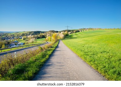 Way in the countryside between a agricultural field and a road, landscape in Germany, blue sky in the spring