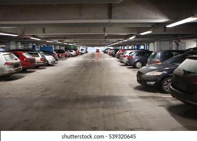 Way to go out from covered free parking lot of city shopping mall. Cars standing in rows.