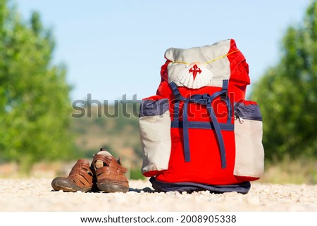 Way of St James , Camino de Santiago ,scallop shell on backpack  on dirt road with old sandals  to Compostela , Leon , Spain