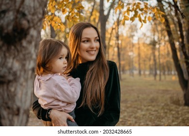 Ways To Carry A Toddler. Close Up Outdoors Portrait Of Happy Family Mom And Toddler Baby Girl In Fall Park. Little Girl And Her Mother In The Autumn Park.