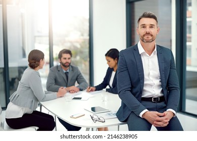 We all value each others expertise. Portrait of a businessman standing in a boardroom meeting with colleagues in the background. - Shutterstock ID 2146238905