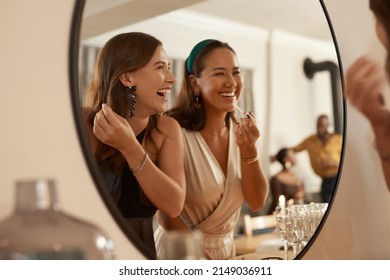 We always have a joke prepared. Shot of two young friends standing together and using a mirror to touch up their makeup at a dinner party. - Powered by Shutterstock