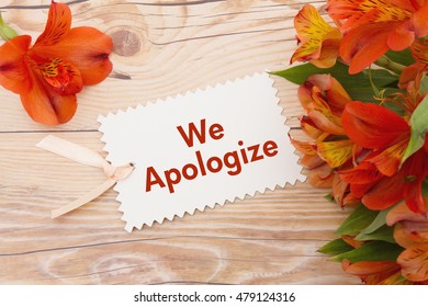 We Apologize Message, Some lilies on weathered wood with We Apologize Gift Card and copy space for your message