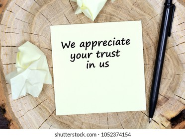 We appreciate your trust in us. Text on paper on a wooden table