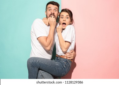 We are in awe. Fright. Portrait of the scared man and woman. Couple standing on trendy pink and blue studio background. Human emotions, facial expression concept. Front view