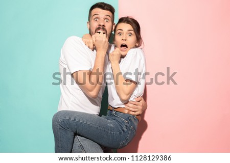We are in awe. Fright. Portrait of the scared man and woman. Couple standing on trendy pink and blue studio background. Human emotions, facial expression concept. Front view